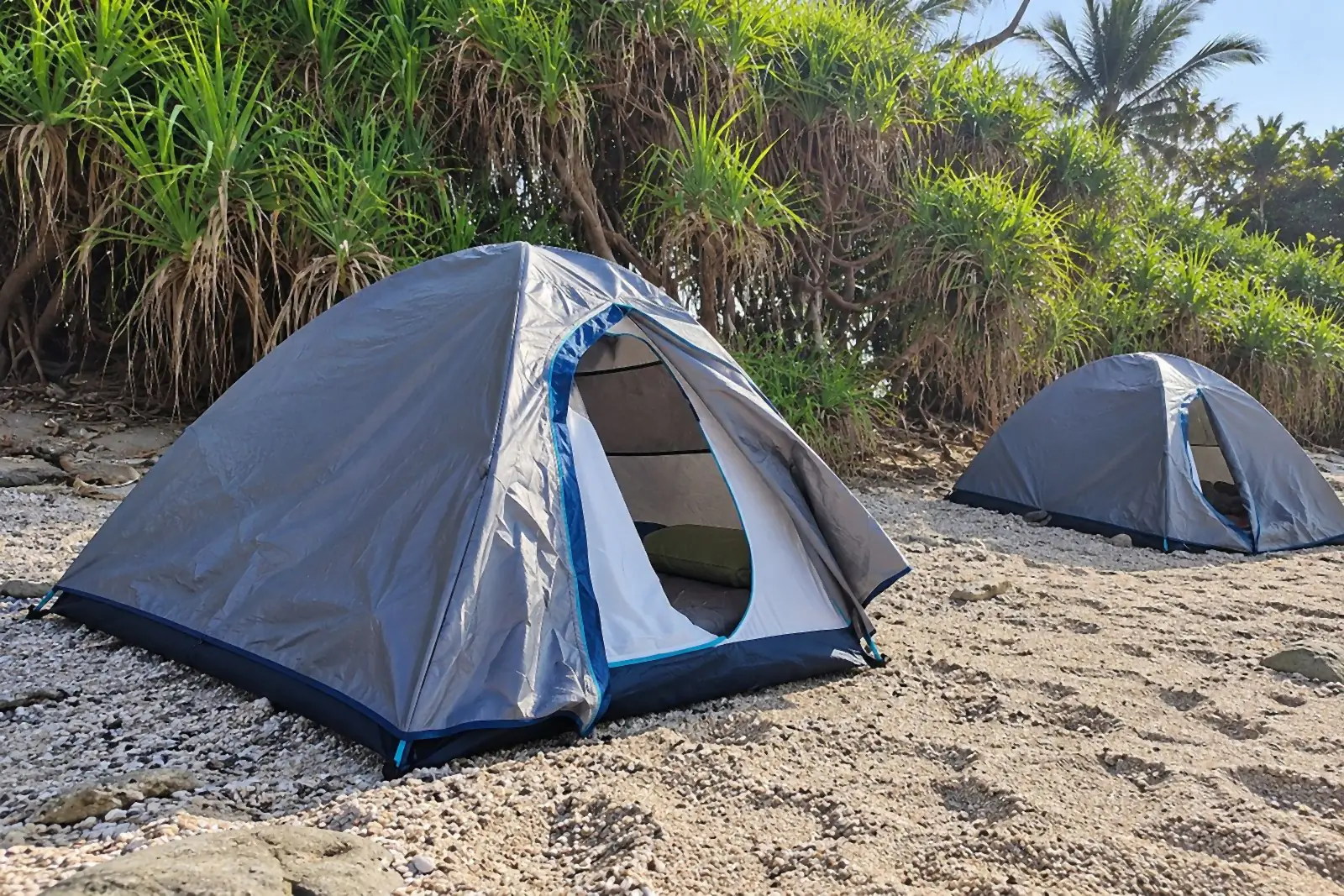 Two beach tents on the sand beside the shrubs (design image)
