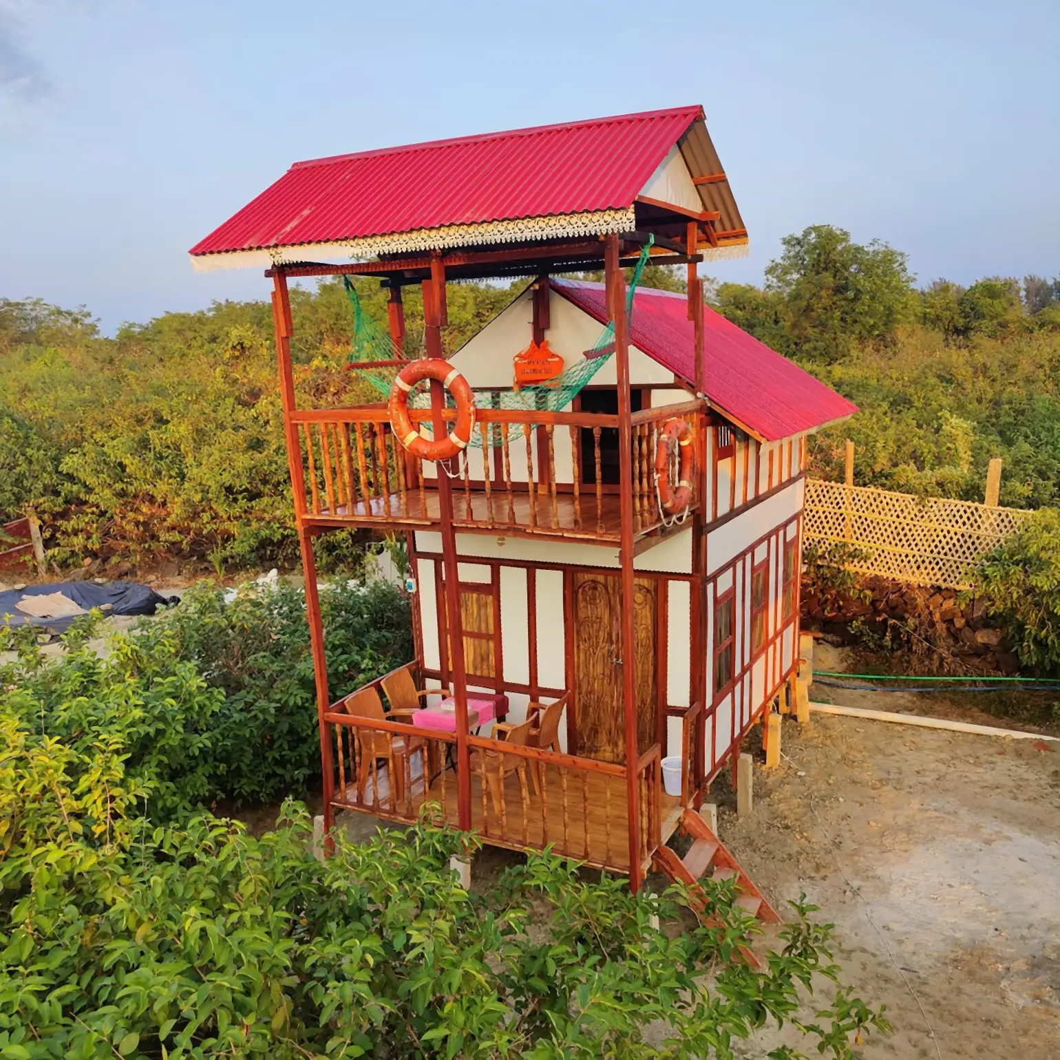 Duplex cottage with a balcony among green shrubs
