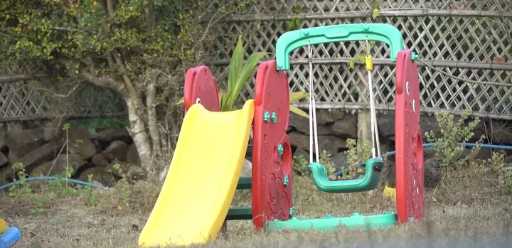 Children's playground with a yellow slide and a swing