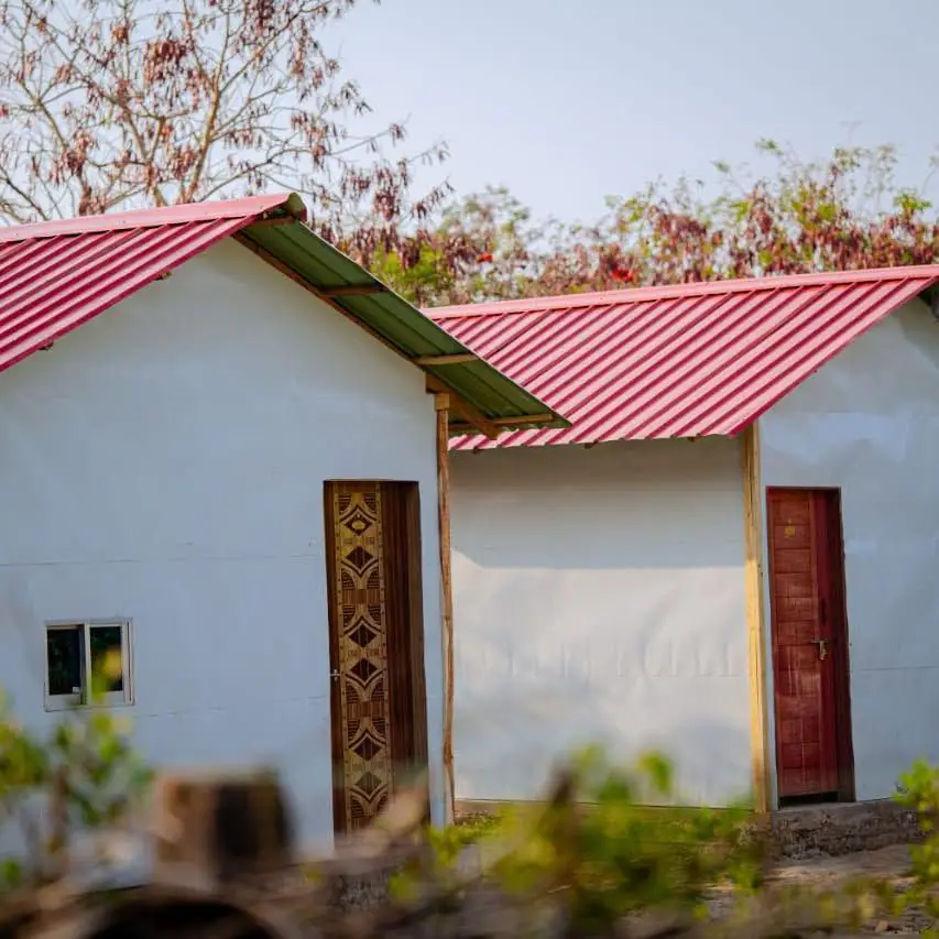 Two single cottages with red tin roofs among the trees